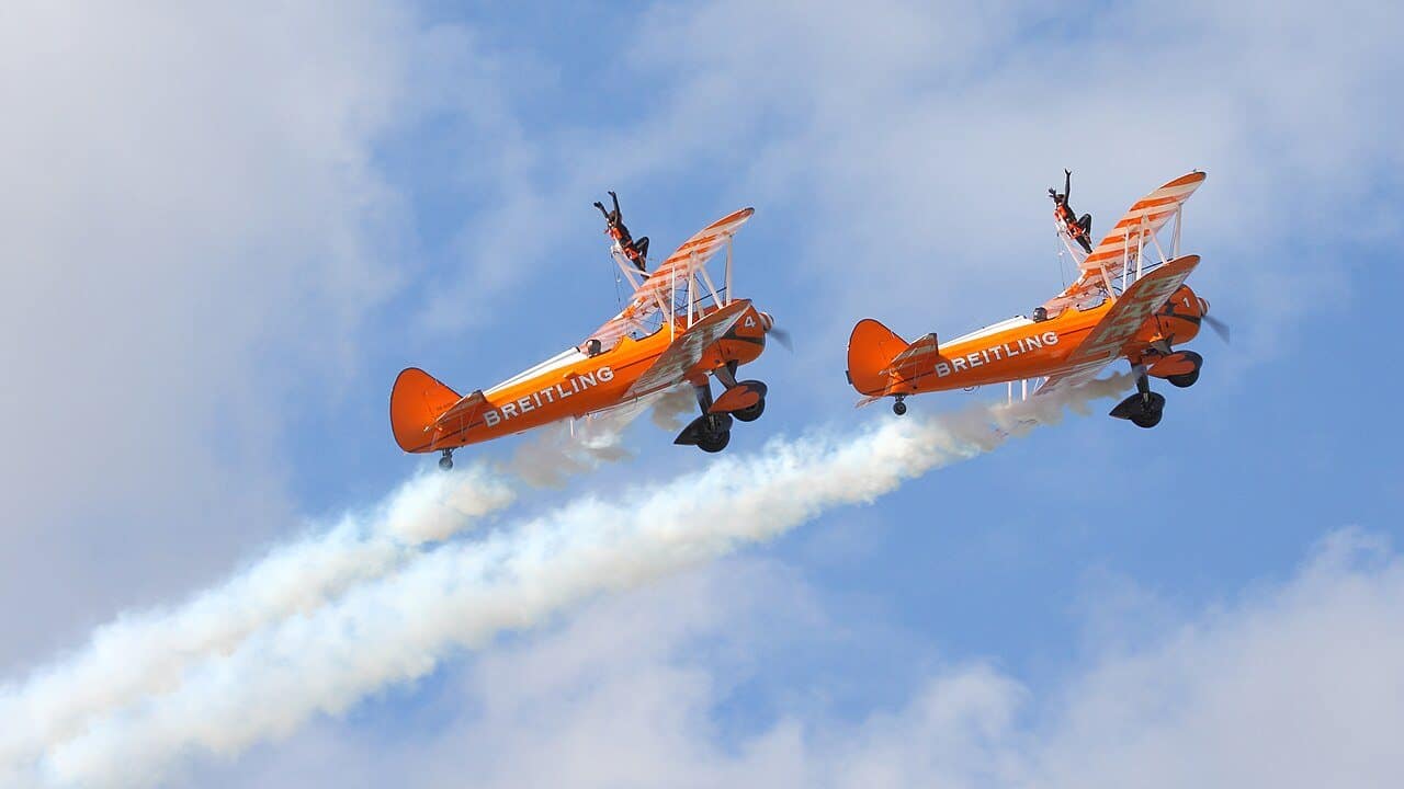 Breitling Wingwalkers perform on orange Boeing Stearman biplanes