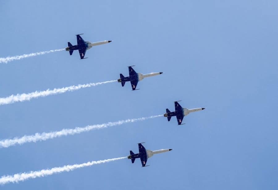 Cuatro aviones F-5 de la NASA en formación cerrada dejando una estela de humo.