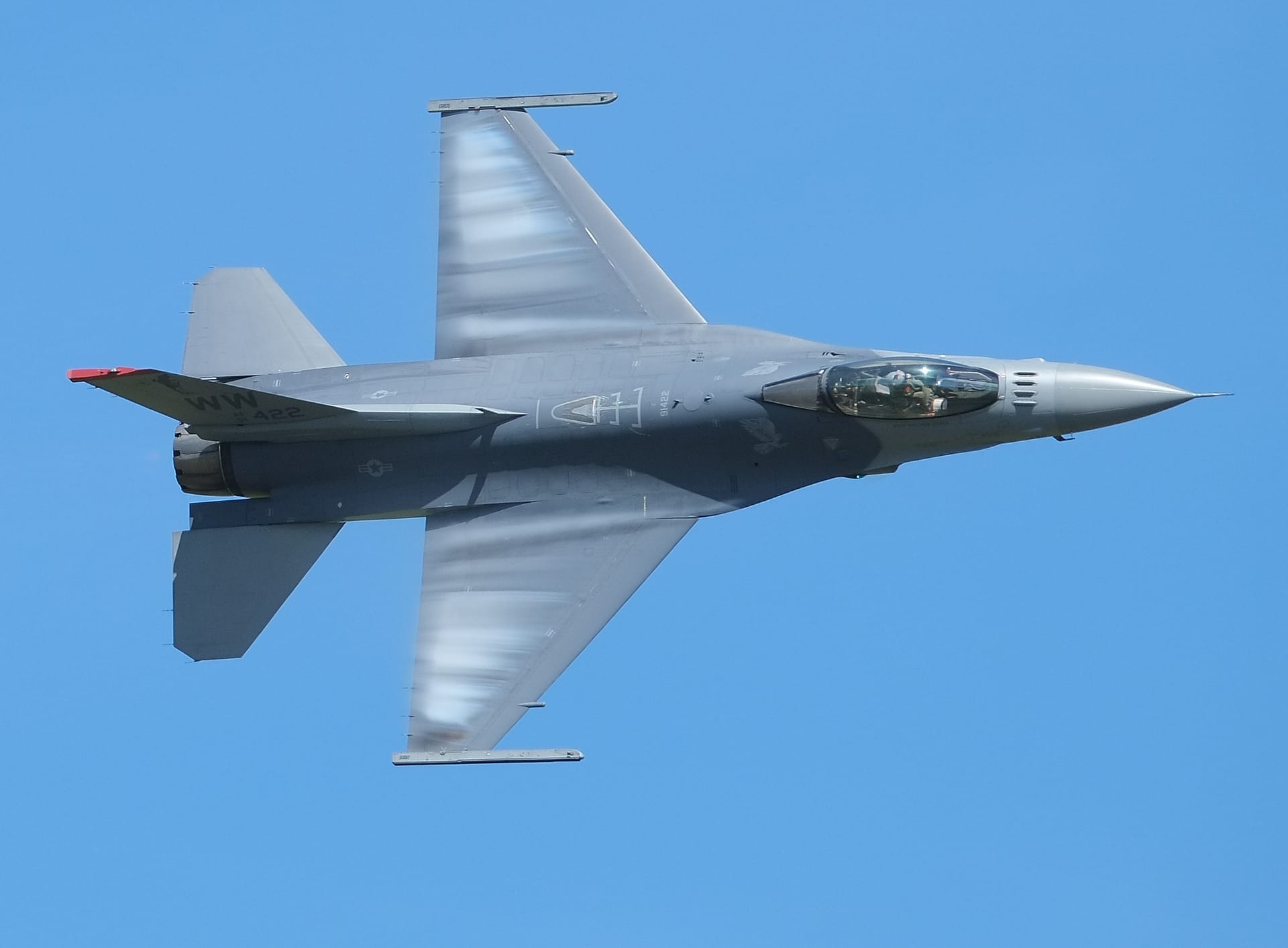 F-16 Fighting Falcon banking with condensation clouds forming over the wings
