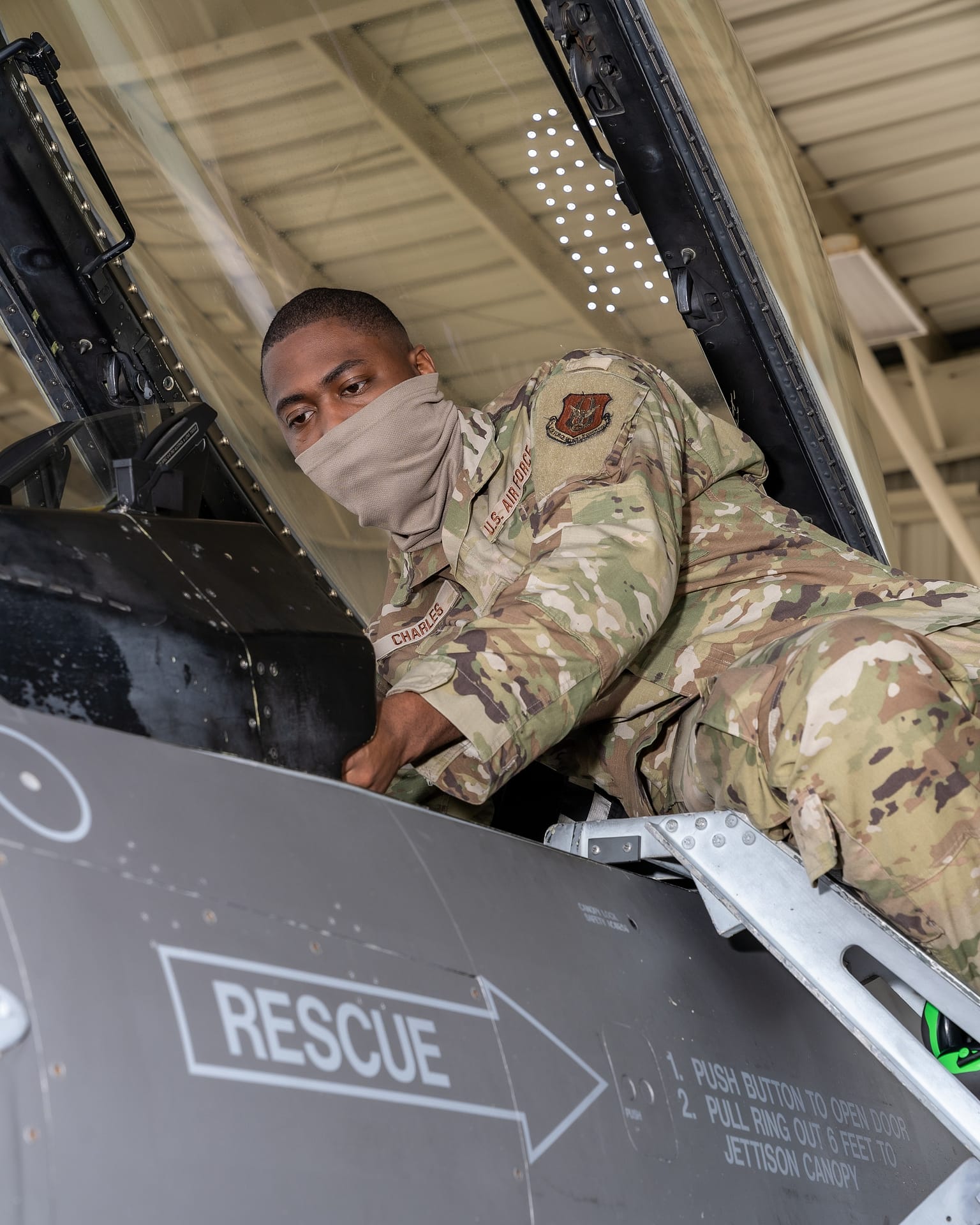 Avionics technician inspecting an F-16 cockpit instrument panel