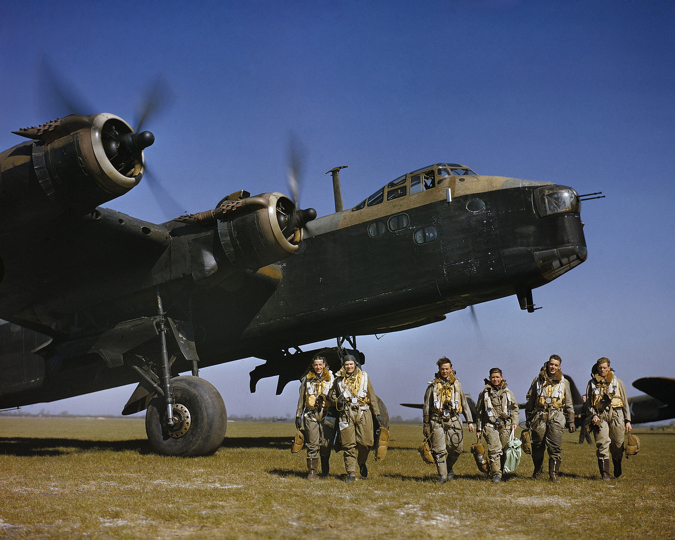Aircrew beneath the towering nose of a Short Stirling, showing the aircraft's great size