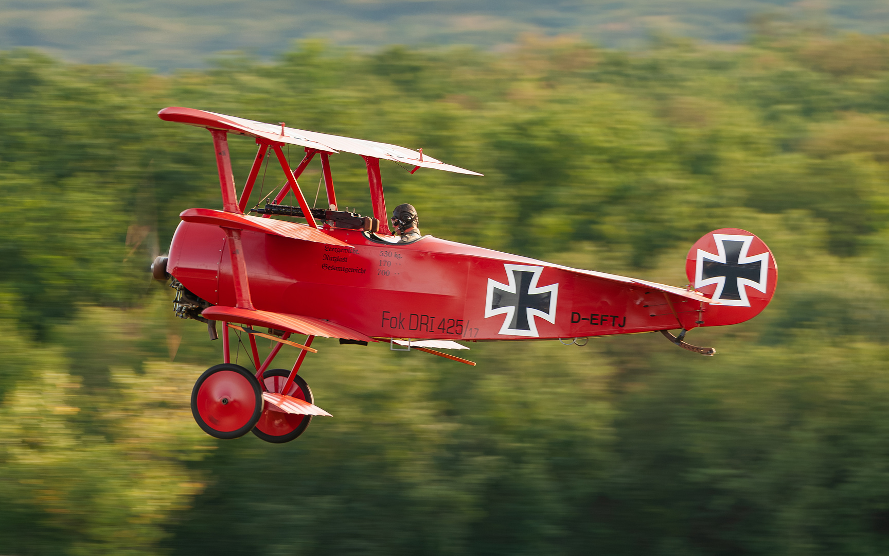 A Fokker Dr.I Triplane flying replica in the air, showing its three stacked wings