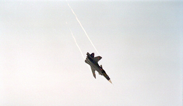 The S-37 climbing away under power during the flight-test years, a contrail streaming behind it.