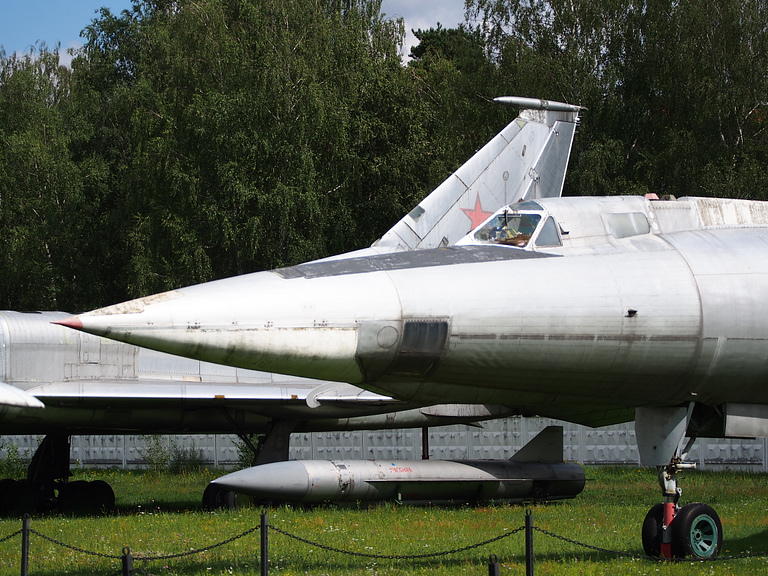 The pointed nose and cockpit of a museum Tu-22, with a Raduga Kh-22 standoff missile displayed beneath.