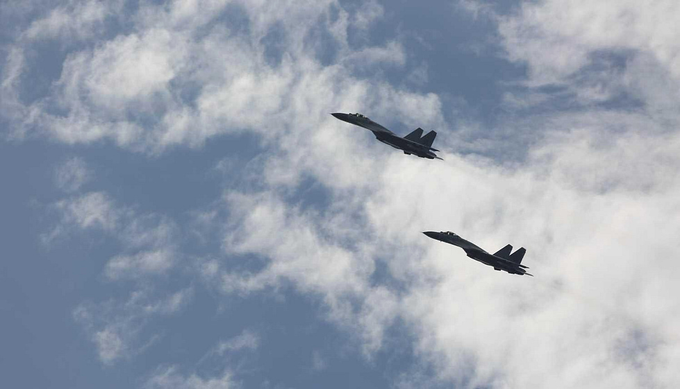 A pair of J-15s against the clouds a large, twin-engine carrier fighter.