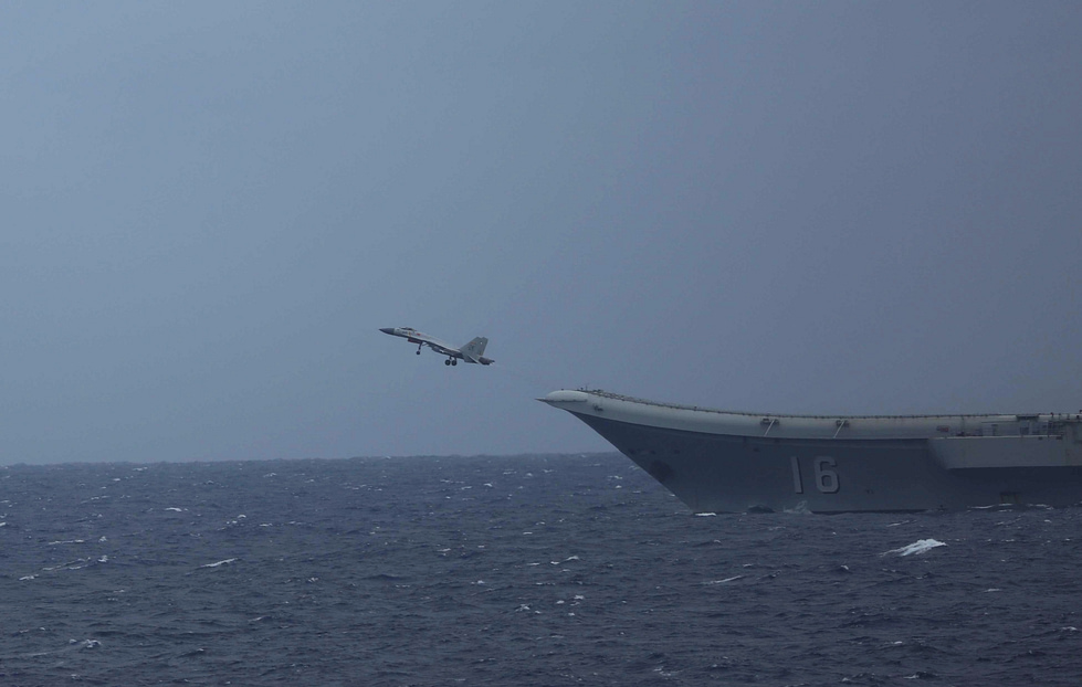 A J-15 over a Chinese carrier at sea the Flying Shark launches by ski-jump and recovers on the arrestor wire.