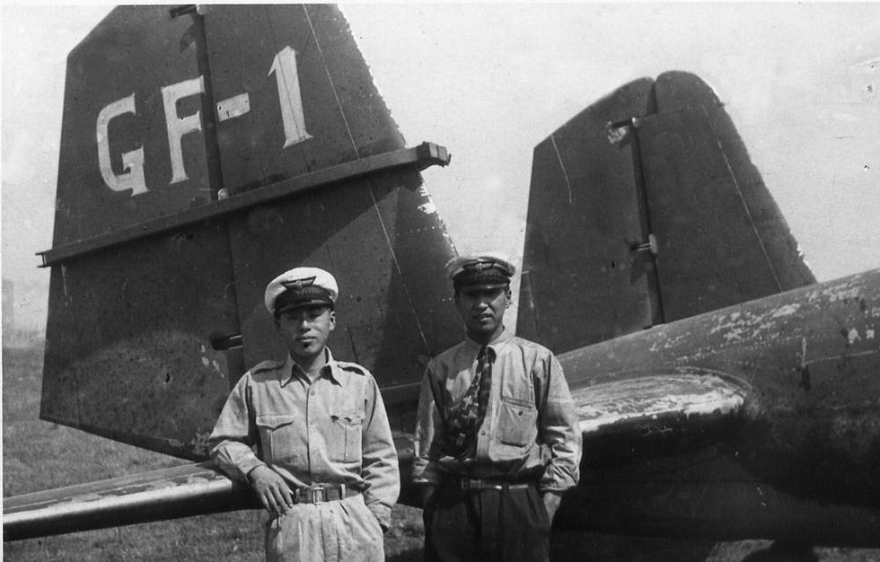 Japanese naval aircrew beside a G3M, its tail and fin visible behind.