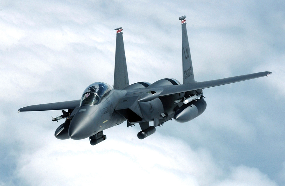 An F-15E Strike Eagle banks away after refuelling conformal tanks hugging the fuselage.