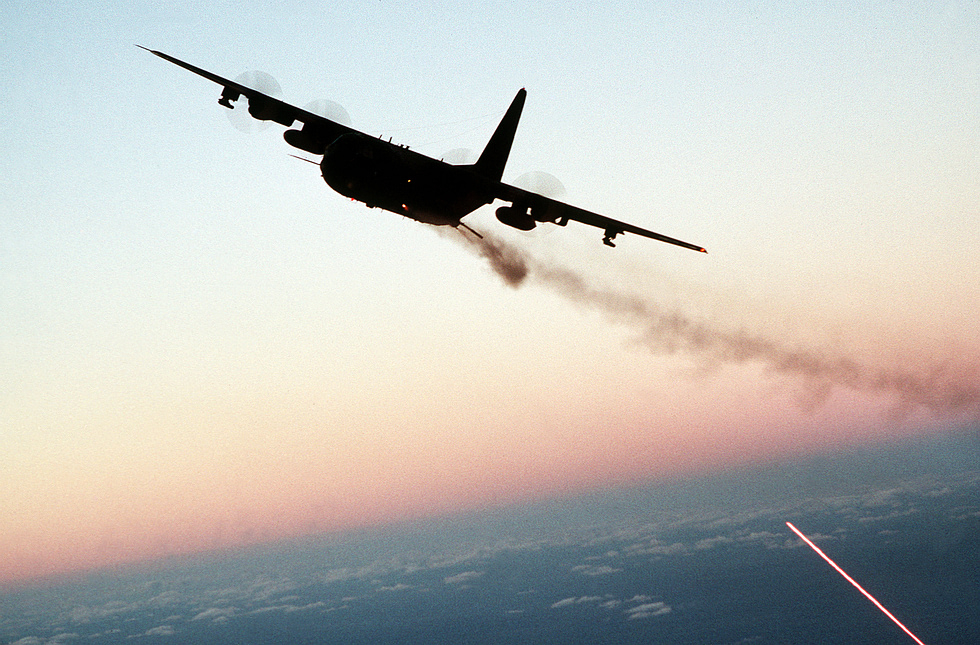 An AC-130 firing broadside at dusk the side-firing guns that define the gunship.