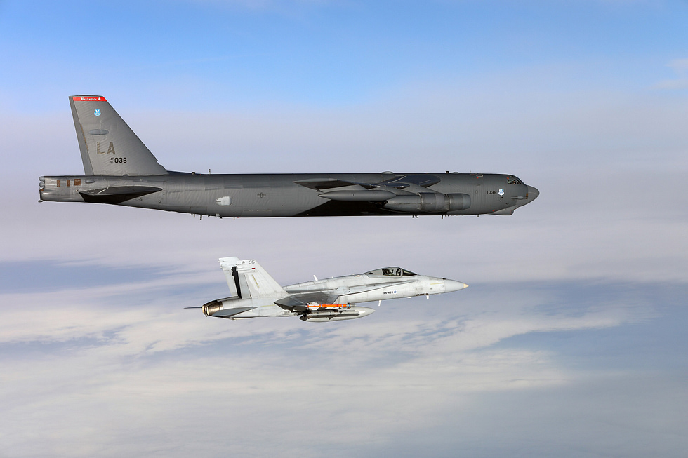 A Finnish Air Force F-18C Hornet flies alongside a US Air Force B-52 the Ilmavoimat has flown the Hornet since the 1990s.