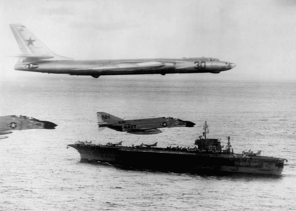 A Tu-16 overflies the carrier USS Kitty Hawk in 1963 the Cold War maritime shadowing the Badger became known for.