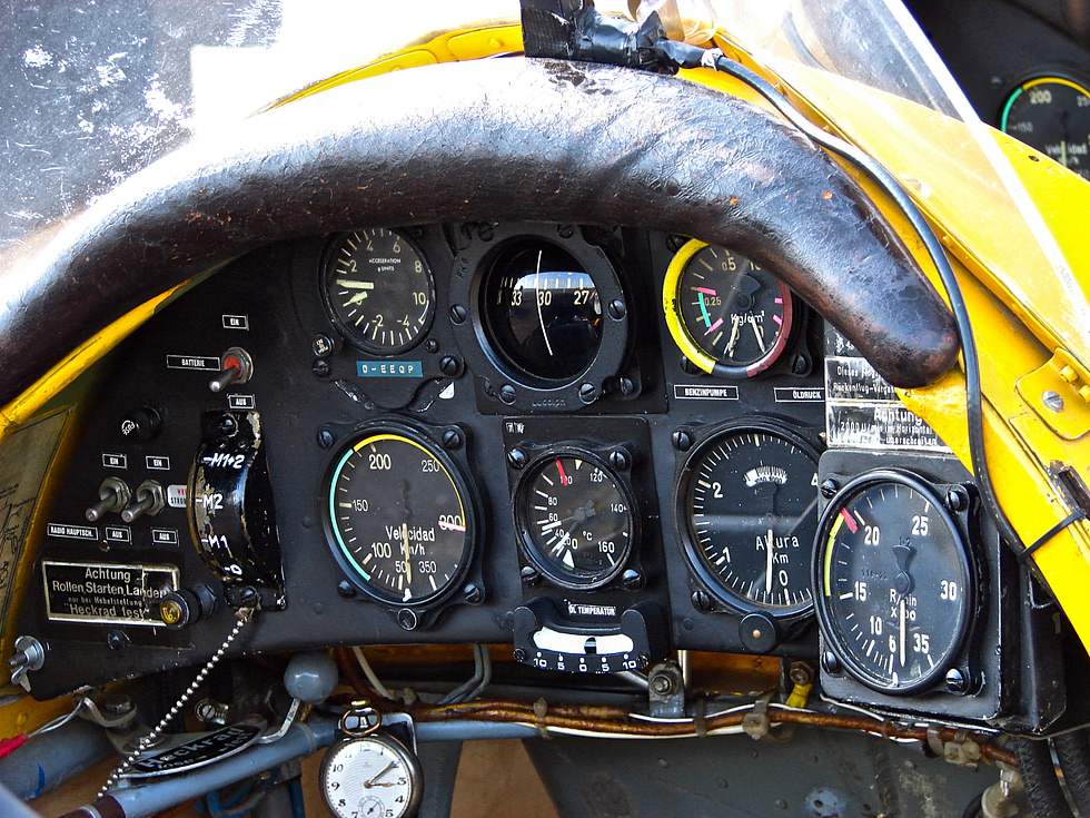 The open tandem cockpit and simple panel of a Bücker Jungmann.