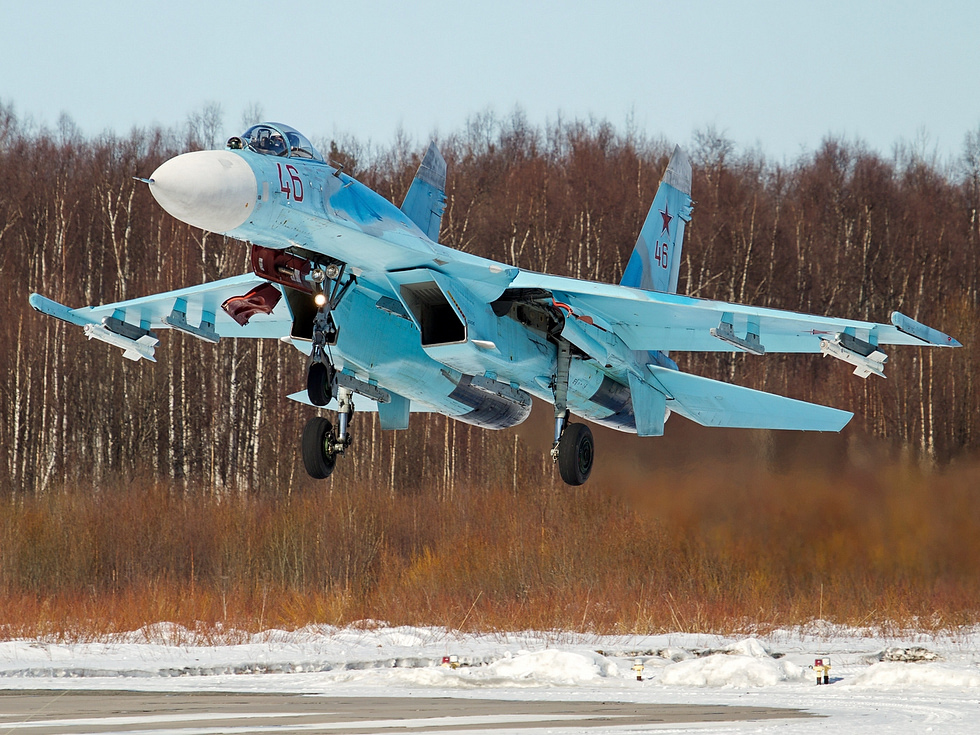 A Russian Air Force Su-27P banking in flight over the countryside.