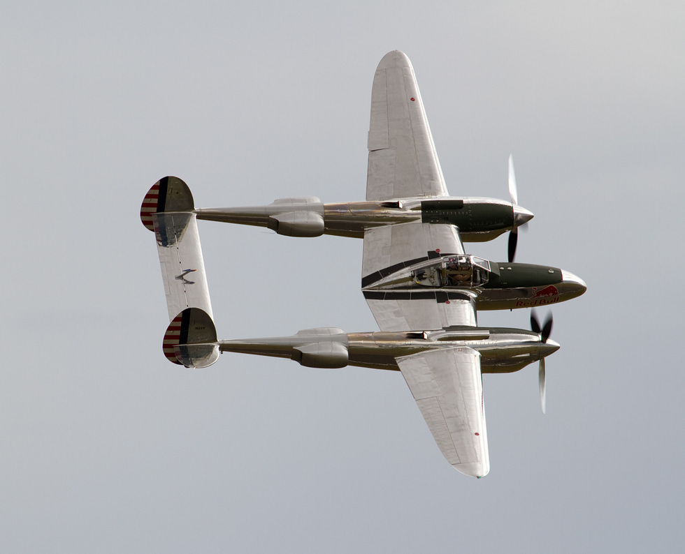 A restored P-38 banks to reveal the twin-boom planform that defined the Lightning.