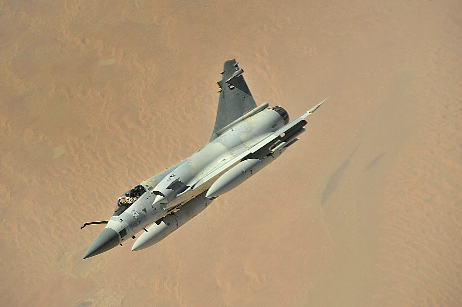 Dassault Mirage 2000 delta-wing fighter banking over desert in flight