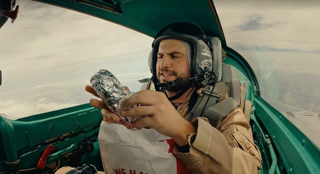 Bob Menery unwrapping a foil-wrapped Arby’s cheesesteak in the MiG-21 cockpit