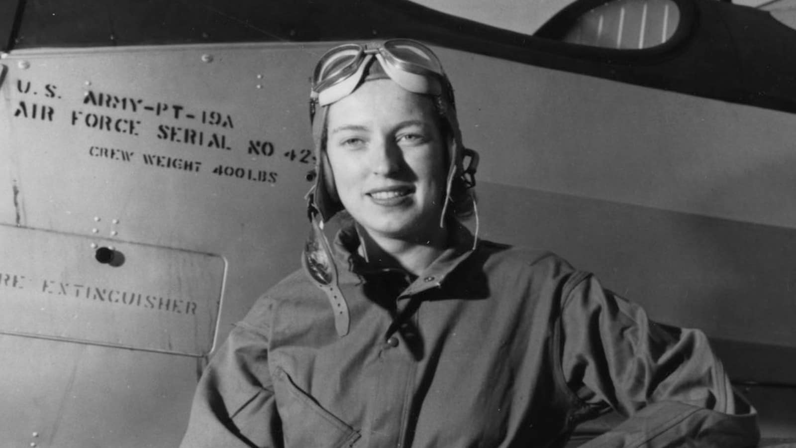 Cornelia Fort in flying coveralls beside a PT-19A trainer during her service with the Women’s Auxiliary Ferrying Squadron