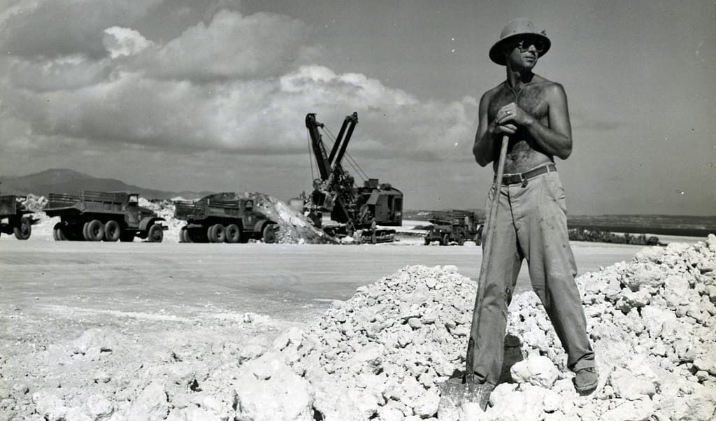 A Seabee directs trucks unloading coral for a B-29 runway on Tinian