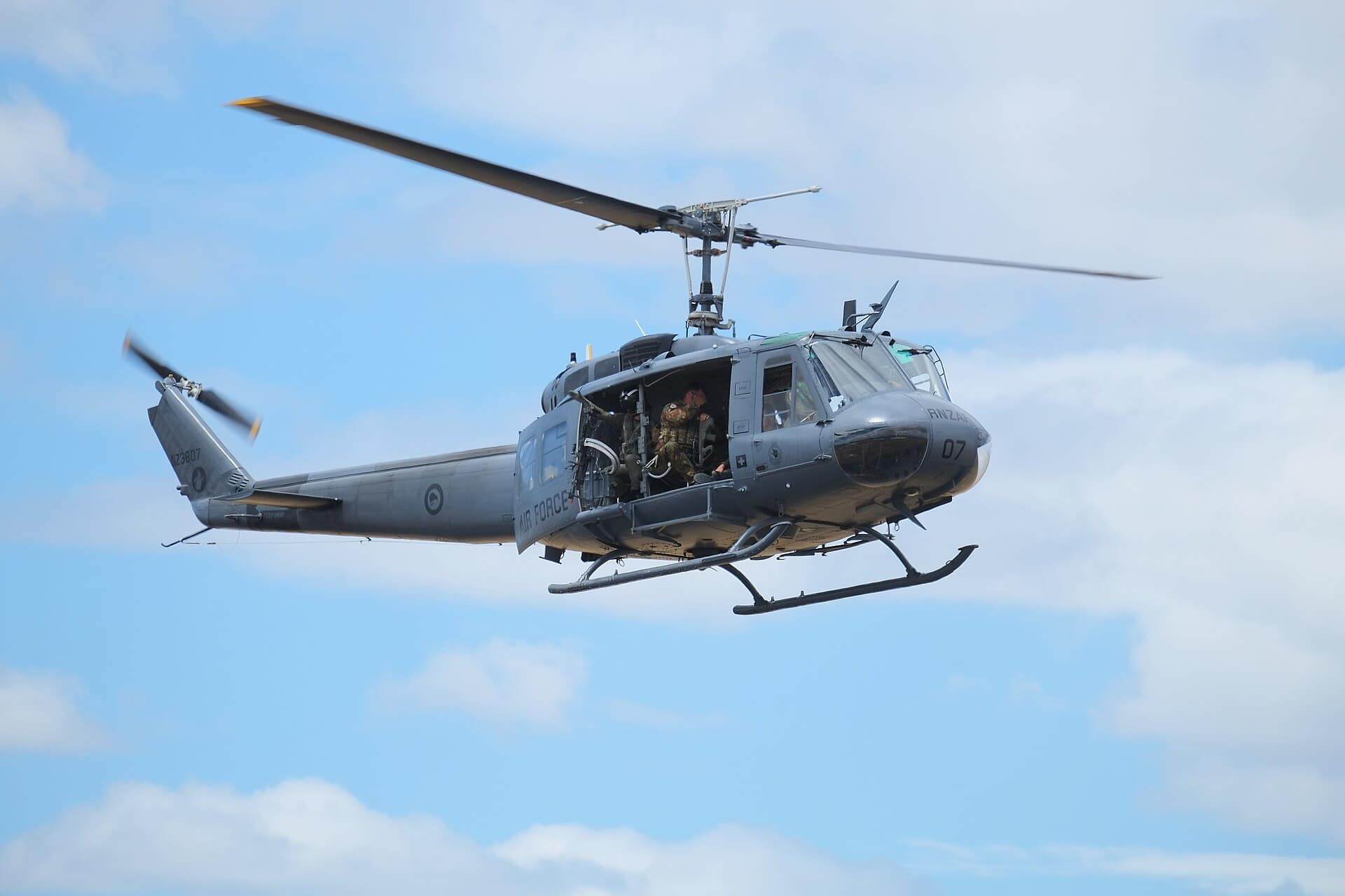 A UH-1 Huey in flight with its doors open